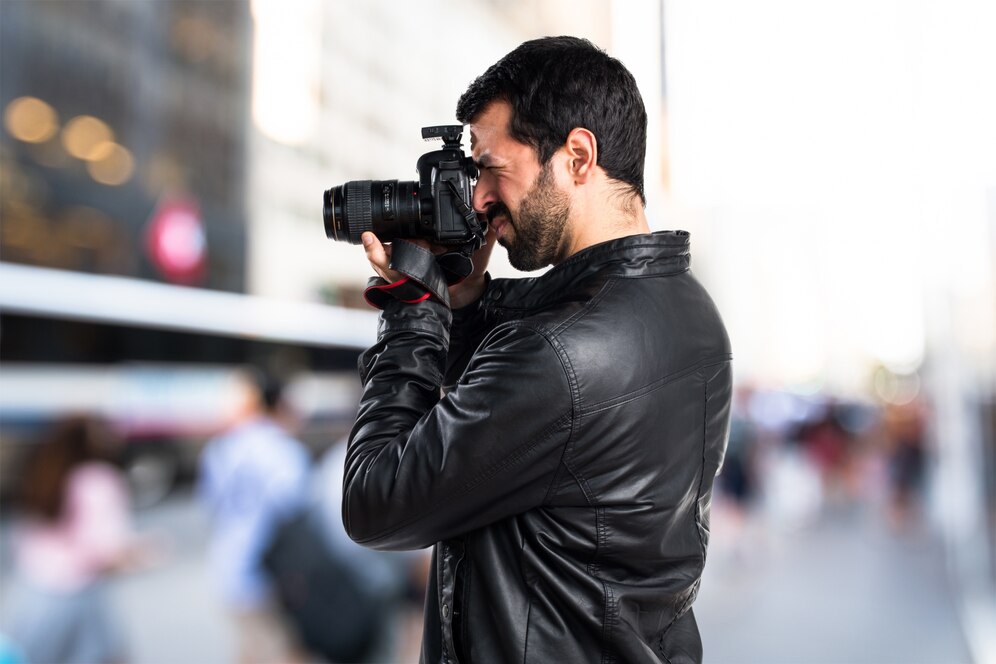 Fotografo tirando foto próximo a uma rua movimentada por carros