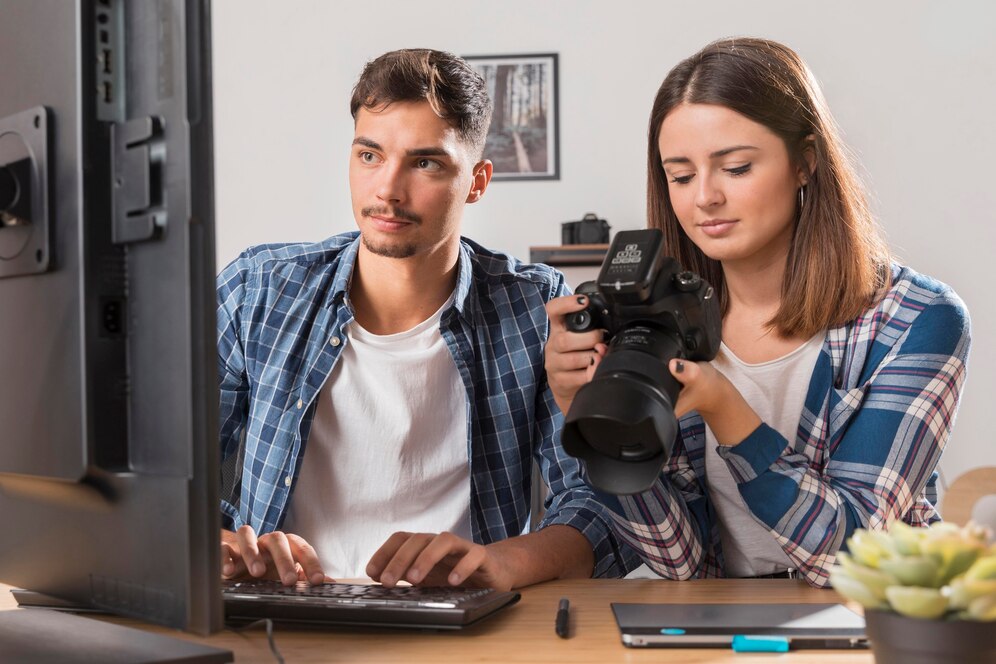 Um homem e uma mulher sentados em uma mesa, trabalhando em um projeto de edição e legenda de vídeos.